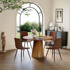 a dining room table with four chairs and a vase on the table in front of an arched window