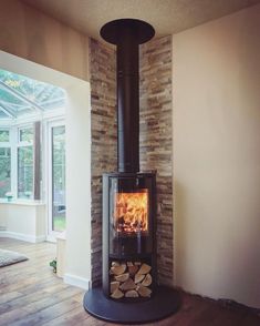 a wood burning stove in a living room next to a large glass window and wooden floor