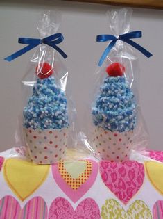 two cupcakes wrapped in plastic with blue and red sprinkles