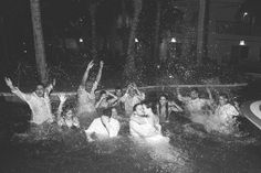 black and white photograph of people playing in the water at night with their arms up