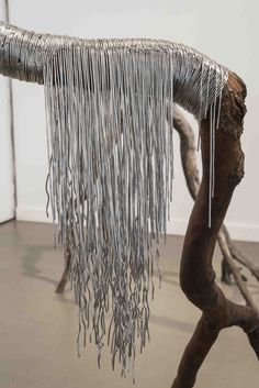 an art piece with chains hanging from it's sides and on top of a tree branch