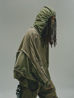 a man with dreadlocks is wearing an army green hoodie and cargo pants