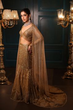 Metallic gold fishcut lehenga with all-over sequin, crystal, and cutdana embroidery with a flowing trail at the back. Paired with a delicate full sleeves blouse with hanging tassel detailing and embroidered dupatta in net.DELIVERY TIMEPlease allow 8-12 weeks for your outfit to arrive.FABRIC DETAILSNetProfessional cleaning only. Festive Embellished Pre-draped Saree With Long Sleeves, Festive Embellished Long Sleeve Pre-draped Saree, Festive Long Sleeve Embellished Pre-draped Saree, Designer Long Sleeve Lehenga With Sheer Dupatta, Long Sleeve Sharara With Dupatta For Reception, Gold Long Sleeve Gown With Zari Work, Gold Zari Work Long Sleeve Gown, Anarkali Style Hand Embellished Pre-draped Saree, Traditional Pre-draped Saree With Sheer Dupatta And Long Sleeves