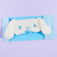 a white stuffed animal laying on top of a blue and white card with a bow