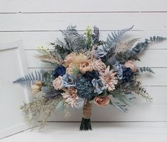 a bridal bouquet with blue and pink flowers on a white table next to a door