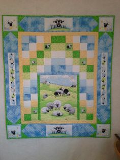 a quilted wall hanging with sheep in a green, yellow and blue checkerboard pattern