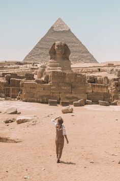 a woman is standing in front of the pyramids