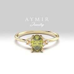 a yellow gold ring with an oval cut green stone and three diamonds on the band