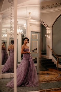 a woman in a purple dress looking at herself in the mirror