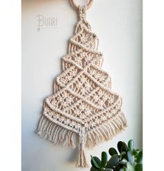 a crocheted christmas tree hanging on a wall with a wooden keychain