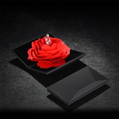 a red rose sitting on top of a black plate next to an empty card holder