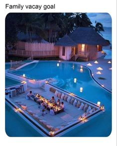 an outdoor dining area in the middle of a pool with candles lit up at night