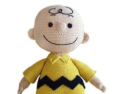 a crocheted doll wearing a yellow shirt and black pants with a smile on it's face