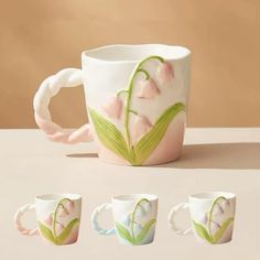 four mugs with flowers painted on them are sitting next to each other in front of a beige background