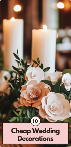 Elegant and cheap wedding decorations with white pillar candles and handcrafted paper flowers surrounded by lush greenery, creating a cozy ambiance.