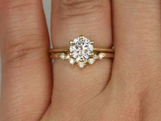 a woman's hand with a diamond ring on top of her finger and the other hand holding an engagement ring