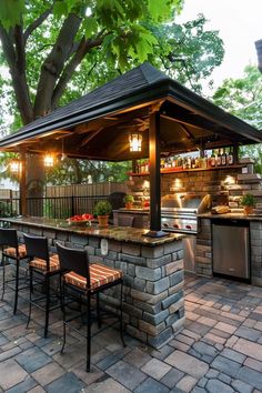 an outdoor kitchen with grill, bar and seating area in the middle of a brick patio