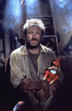 a man with white hair and beard holding a red teddy bear