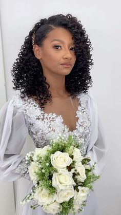 a woman holding a bouquet of flowers in her hand and wearing a white dress with sheer sleeves