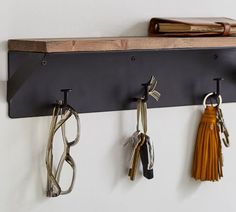 three pairs of glasses hanging on a wall with key holders attached to the pegs