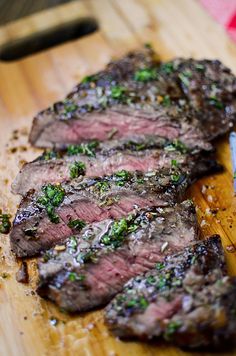 some steaks are on a wooden cutting board with a knife and fork next to it