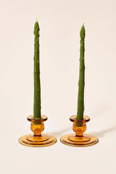 two green candles sitting on top of each other in small glass vases next to each other