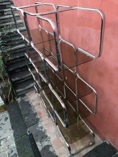 a metal stair case on the side of a pink wall with steps leading up to it