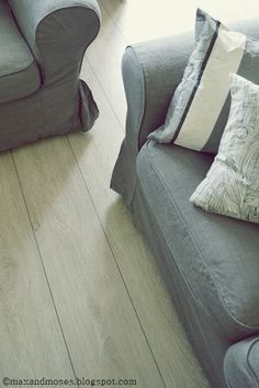 a living room with two gray couches and pillows on the floor next to each other