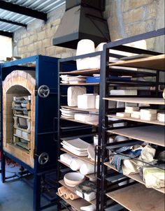 an oven in a room with shelves full of plates