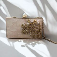 Presenting our Mother of Pearl Clutches--a true masterpiece of elegance. This rectangular clutch showcases a luxurious gold frame, adorned with genuine mother of pearl and embellished with intricate pearl accents. The brass floral detailing, electroplated for lasting durability, adds a refined touch, making this clutch a stunning blend of sophistication and craftsmanship. The inner lining, crafted with plush suede fabric, enhances the tactile experience, making it as delightful to touch as it is Luxury Gold Embroidered Clutch For Wedding, Pearl Clutch, Floral Work, Bridal Bag, Bridal Clutch, Pearl Bridal, Suede Fabric, Timeless Accessories, Bridal Pearls