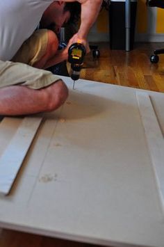 a man laying on the floor using a power drill to cut out a piece of wood