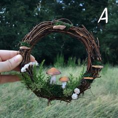 a hand holding a wreath with mushrooms and moss