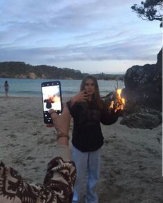 a woman taking a photo with her cell phone on the beach