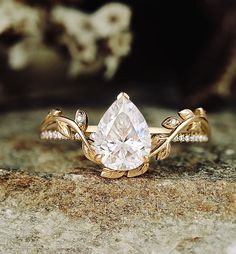 a gold ring with a pear shaped diamond surrounded by small white and clear diamonds on top