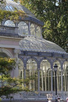 people are walking around in front of a glass house