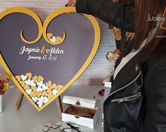 a woman standing next to a table with a heart shaped sign on top of it