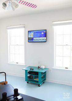 a flat screen tv mounted on the wall in a room with blue floors and white walls