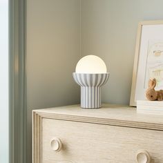 a white and blue lamp sitting on top of a dresser next to a teddy bear