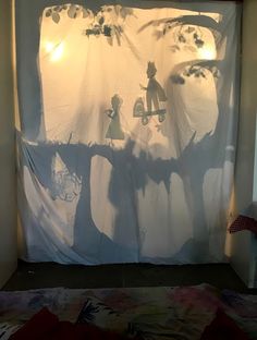 the shadow of a person on a tree in front of a curtain that has been drawn onto it