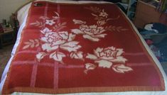 a bed with a red and white blanket on it's headboard next to a bookshelf