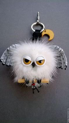 an owl keychain with yellow eyes and white fur on it's back