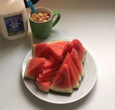 watermelon slices and nuts on a plate next to a cup of milk