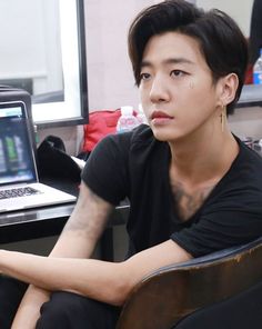 a man sitting in front of a laptop computer on top of a wooden chair next to a desk