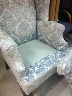 an upholstered chair and footstool are sitting in the middle of a room