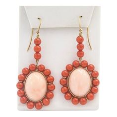 This is part of Chairish’s Fine Jewelry assortment.  These earrings feature a large oval cabochon angel skin coral piece measuring approximately  .80" x .60" set in a frame of orange coral beads measuring approximately 5.5 mm each.  The earrings dangle off an 18k yellow gold wire.  Pierced ears are required to wear these. Red Cameo Oval Jewelry, Coral Oval Jewelry For Gifts, Oval Coral Jewelry For Gift, Elegant Coral Oval Jewelry, Elegant Oval Coral Jewelry, Antique Oval Orange Jewelry, Antique Orange Oval Jewelry, Orange Oval Cabochon Jewelry For Formal Occasions, Orange Oval Antique Jewelry