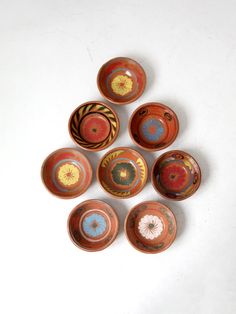 six small bowls with designs on them sitting on a white surface