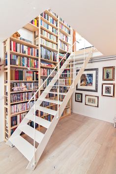 there is a stair case with many books on it in the room next to the stairs