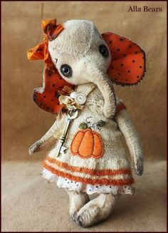 a small stuffed elephant wearing an orange and white dress