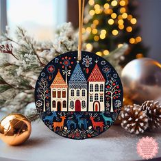 a christmas ornament with houses and deers in front of a decorated tree