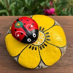 a painted rock with a ladybug on it sitting on top of a yellow flower